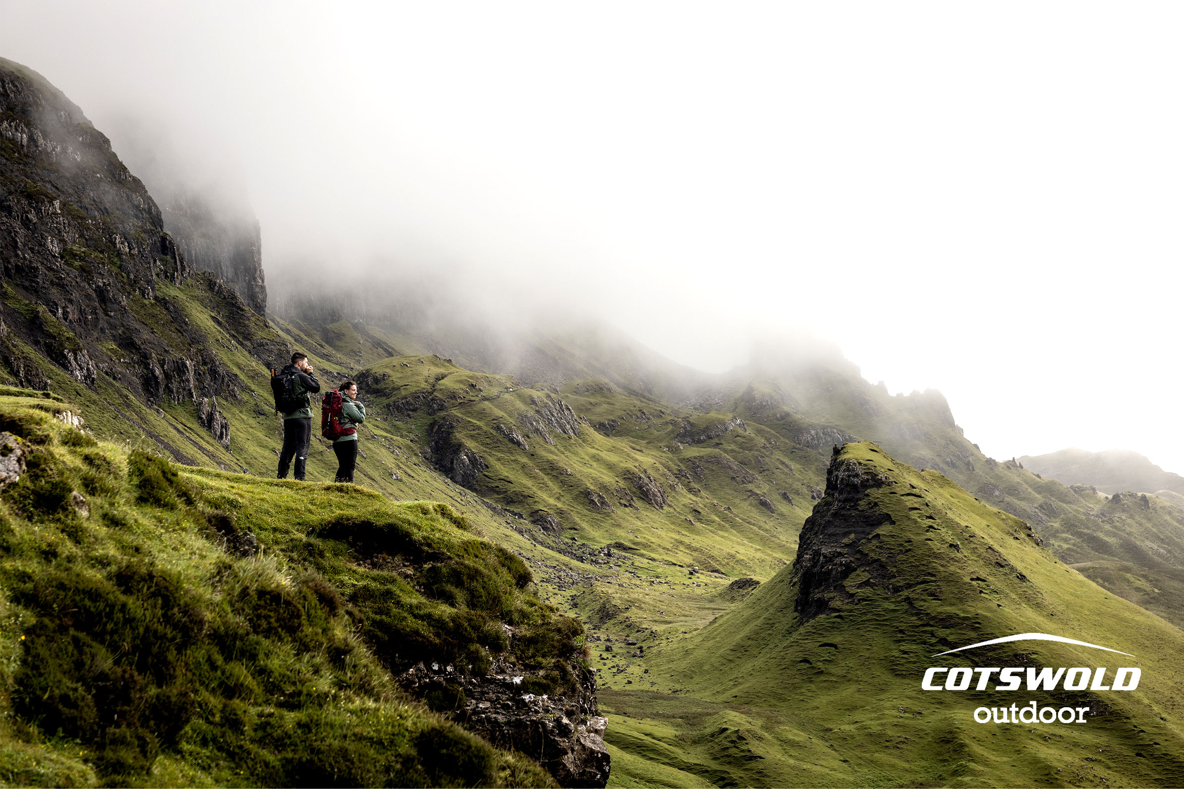 Two people exploring a green hilly countryside.