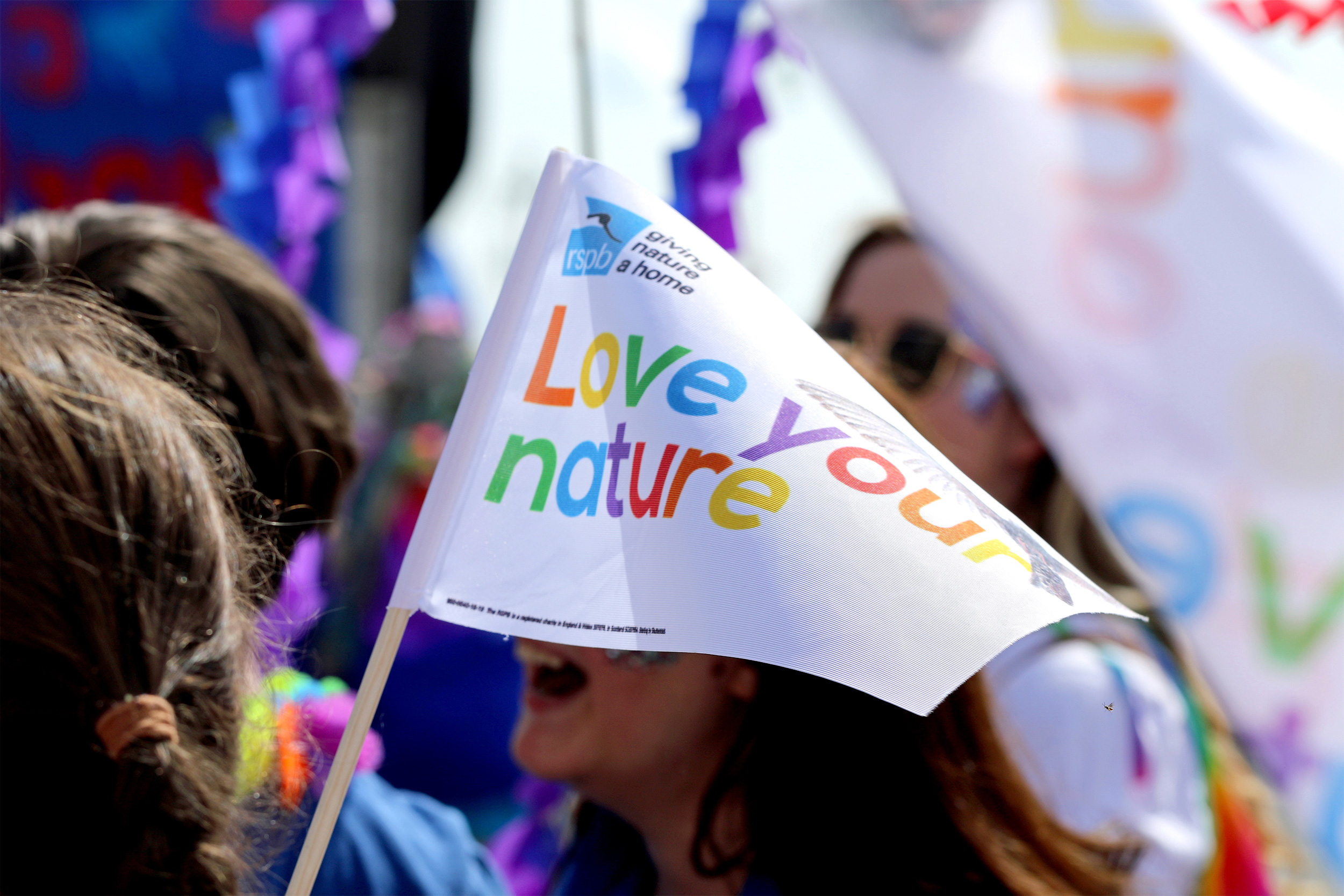 A colourful flag being waved at a Pride parade.