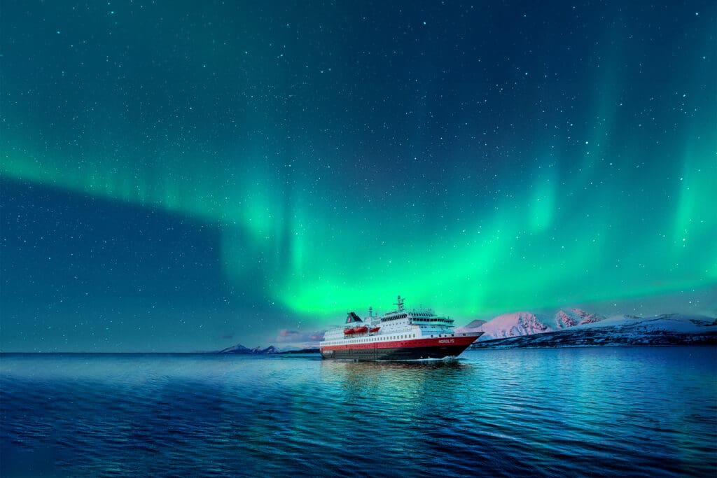 Cruise ship with spectacular green lights in the sky behind.