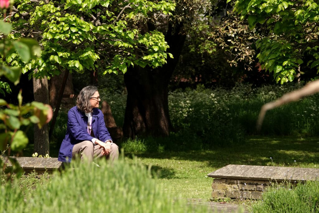 A person sits in a sunny garden