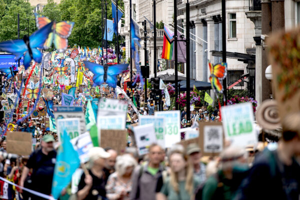 A march of thousands of people holding banners and giant colourful butterfly puppets on a London street