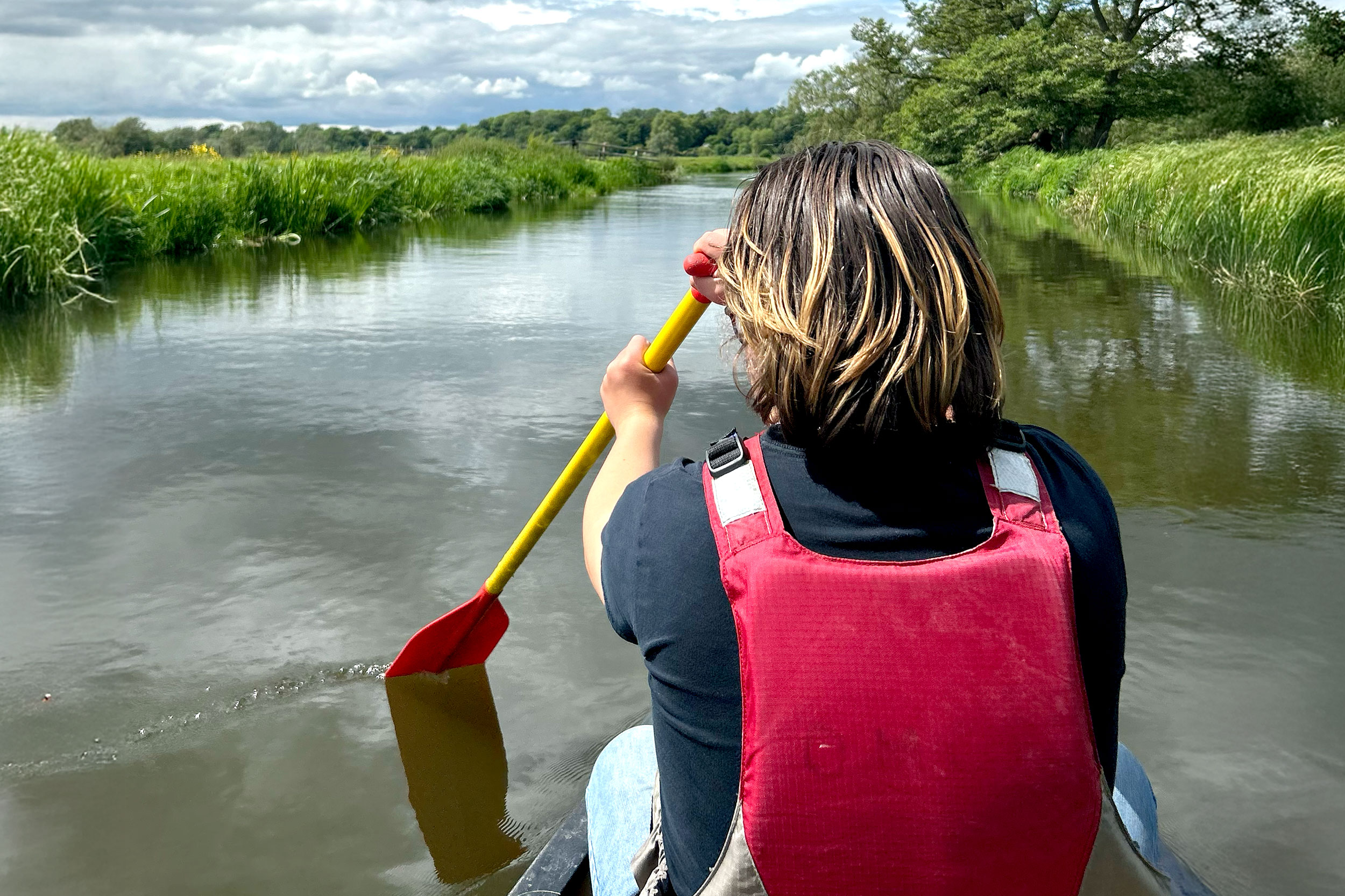 Simon's son Eddie paddling a kayak through a wetland, seen from the back.