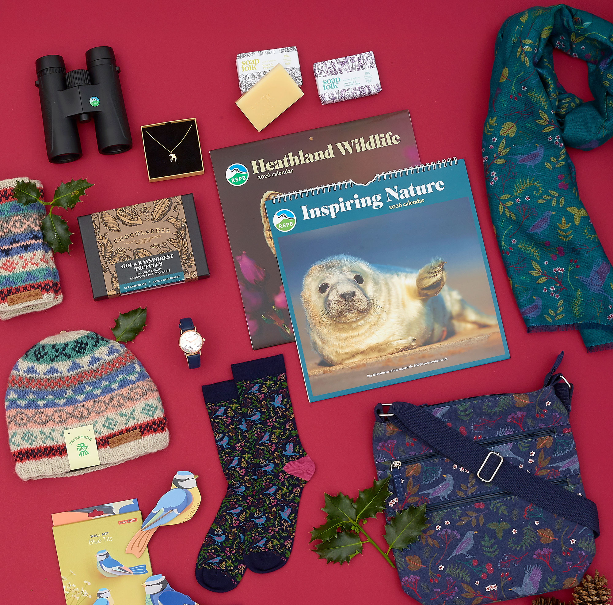 A range of festive gift ideas, including wildlife calendars and binoculars, on a red background.
