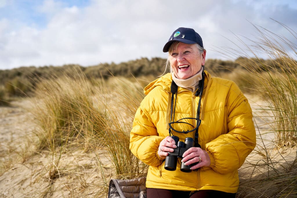 Jacinta Cook, holding binoculars and smiling