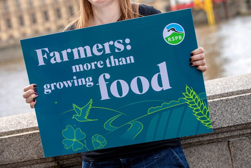 A campaigner holds a sign that reads 'Farmers: more than growing food'