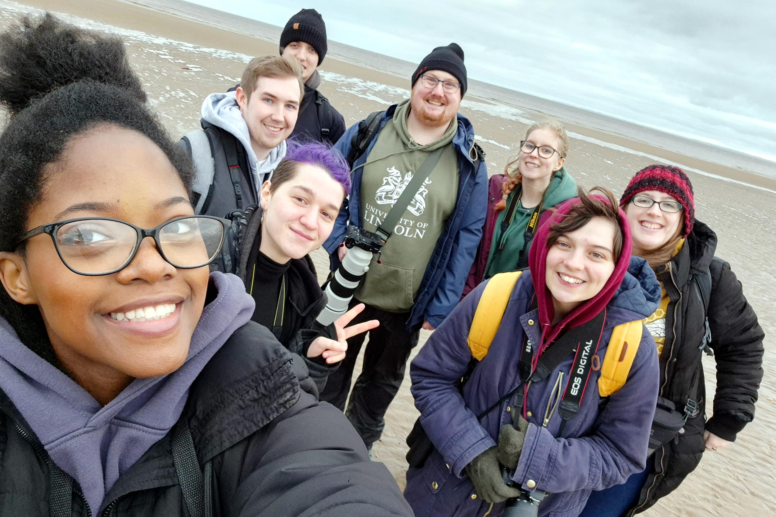 A selfie of a group of university students on a beach