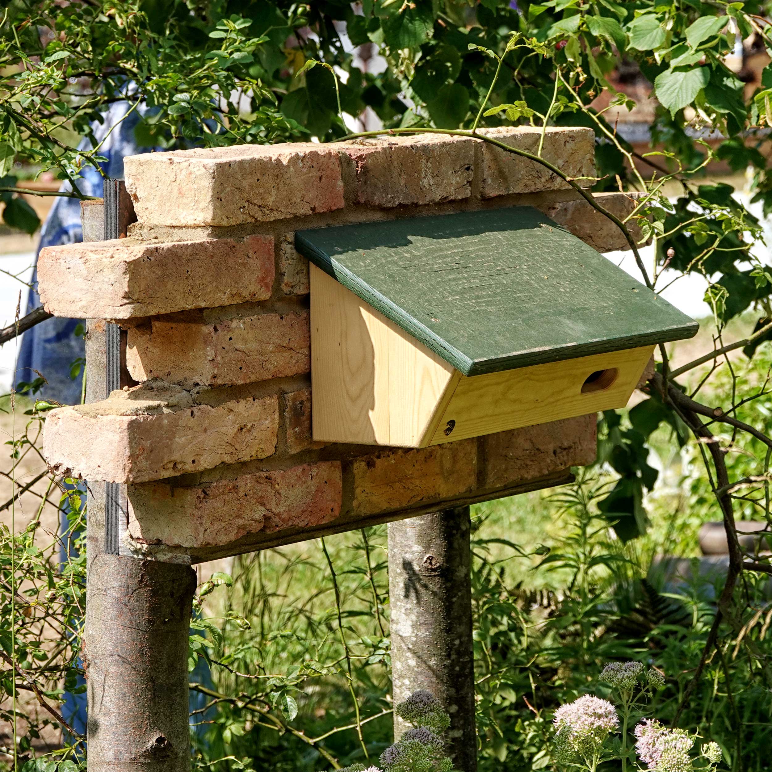 A wooden Swift box installed on some bricks