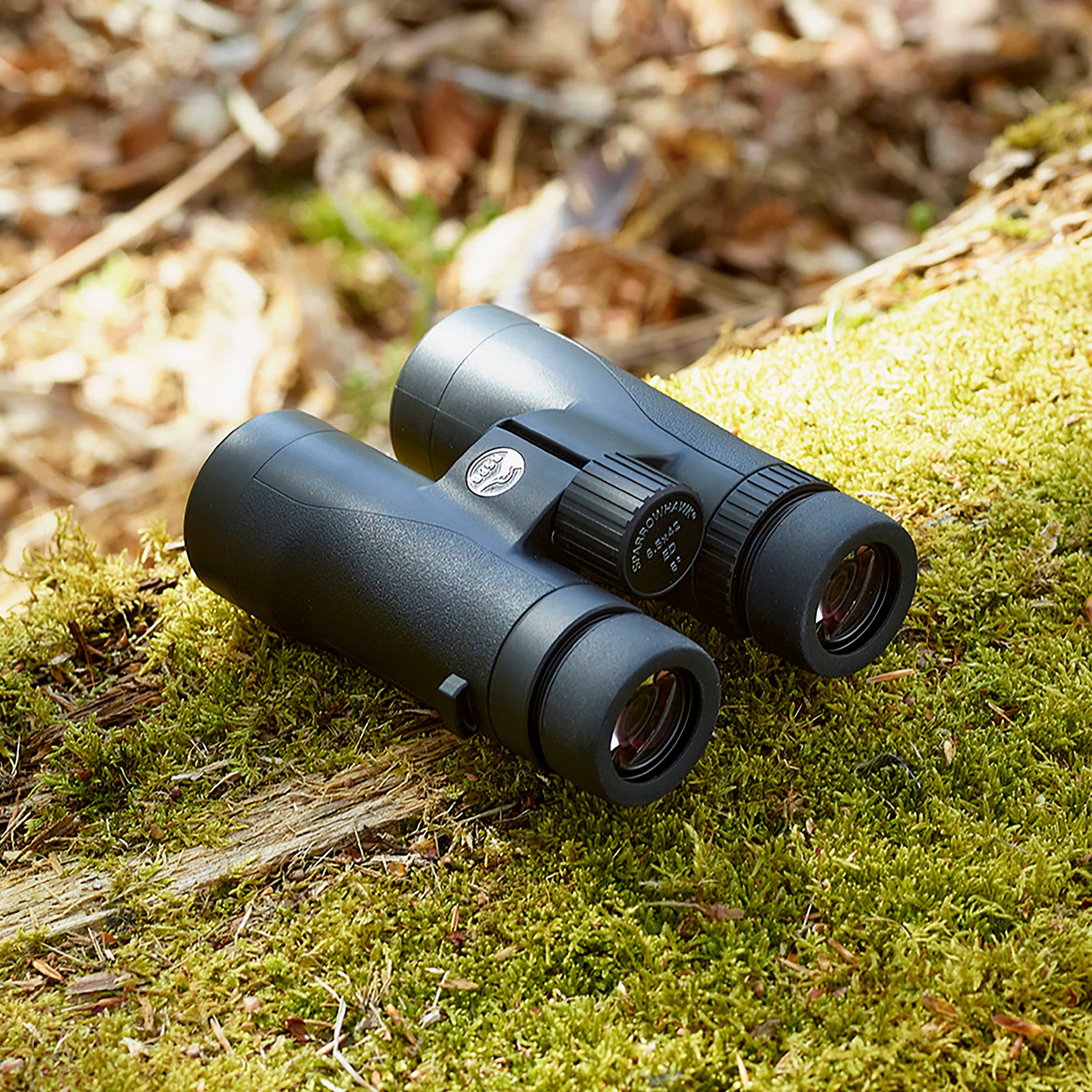 A pair of binoculars on a moss-covered log