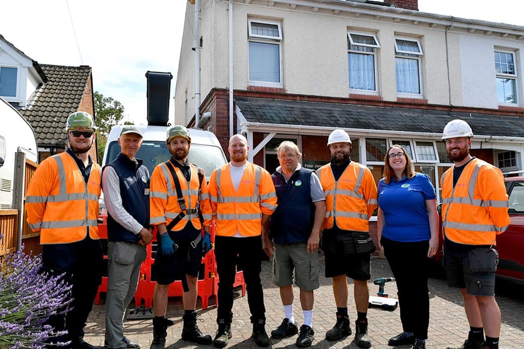 A group or engineers and RSPB staff stood outside a house