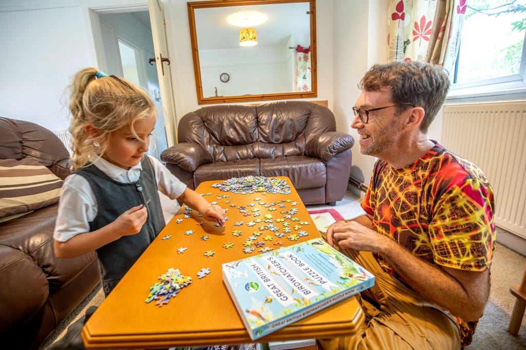 A young girl and a man do a jigsaw puzzle