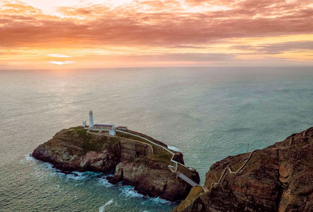 An aerial shot of the lighthouse at RSPB South Stack against a sunset