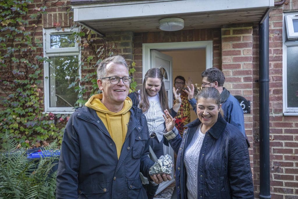 A man waves off a group of adults leaving his house