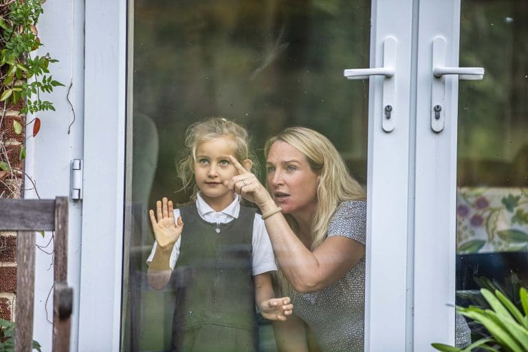 A woman and her young daughter look out of a window at birds