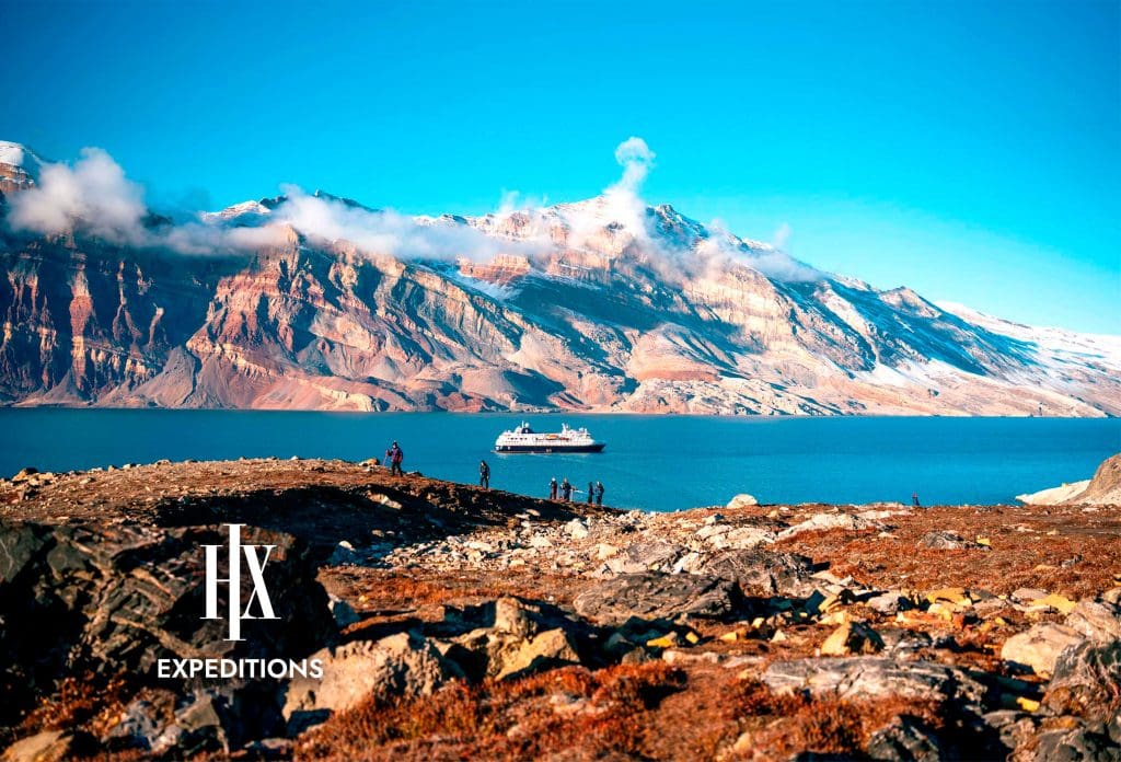 A cruise ship on a large body of water with mountains in the background