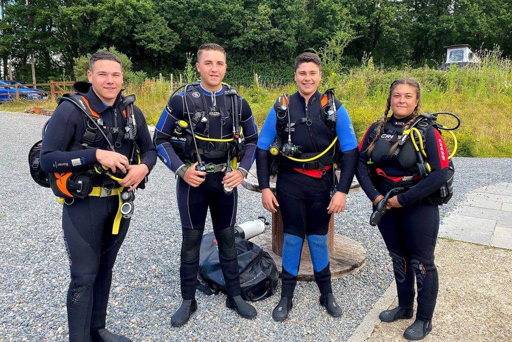 Four young people stood in a car park in scuba gear