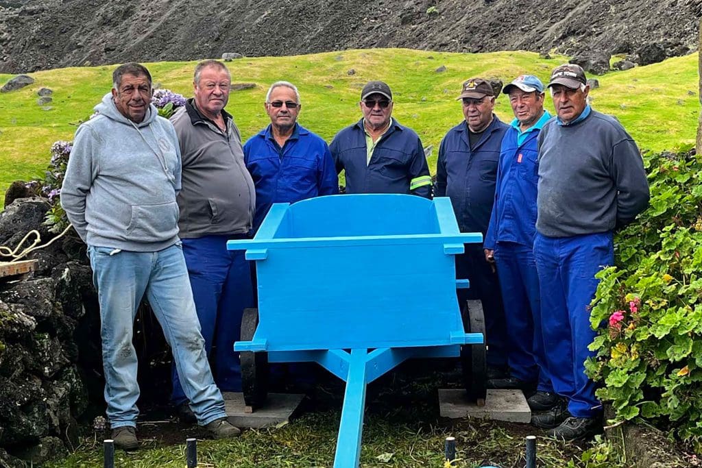 Seven men stand around a blue-painted oxcart