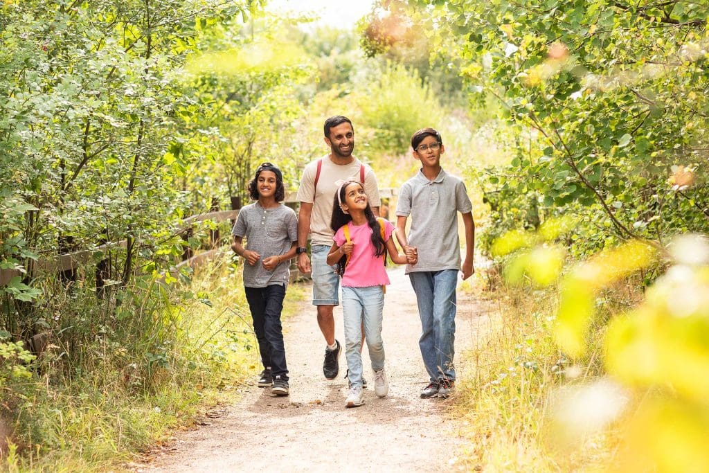 A family of four walking along a path at a nature reserve.