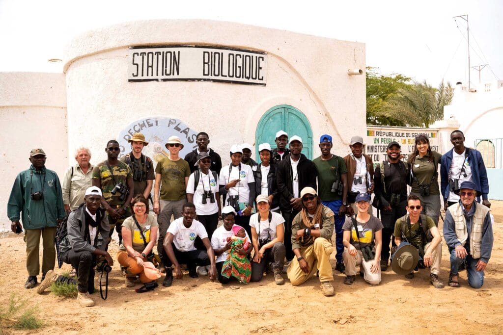 A group of students stand and kneel outside a building named 'Station Biologique'