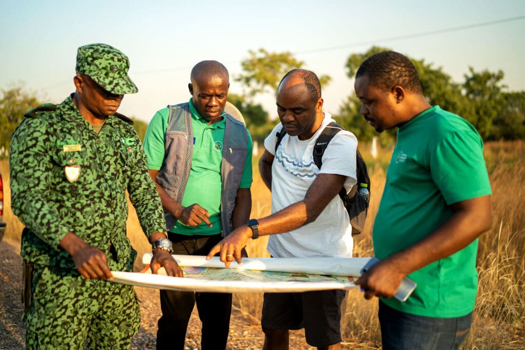 Four men viewing a map out in the field