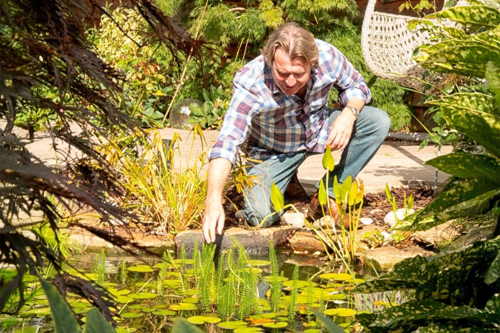A man kneeling at the edge of a pond
