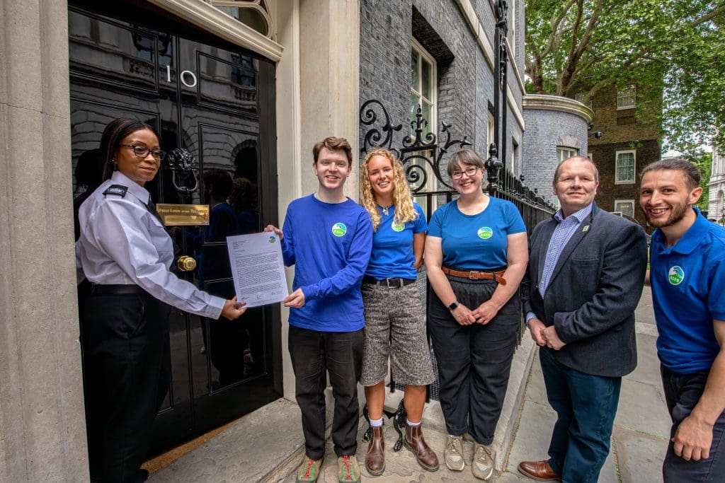 Five RSPB campaigners hand a petition to a woman stood outside 10 Downing Street