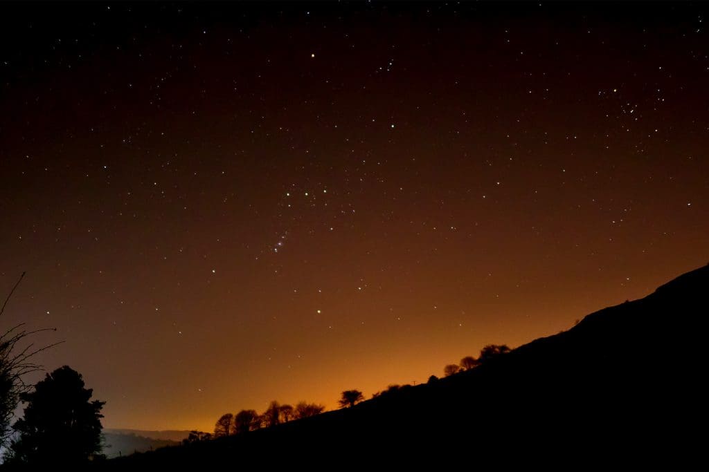 A dark starry sky shows the constellation of Orion