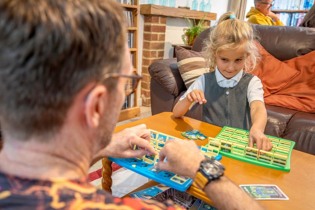A young girl and a man play Guess Who