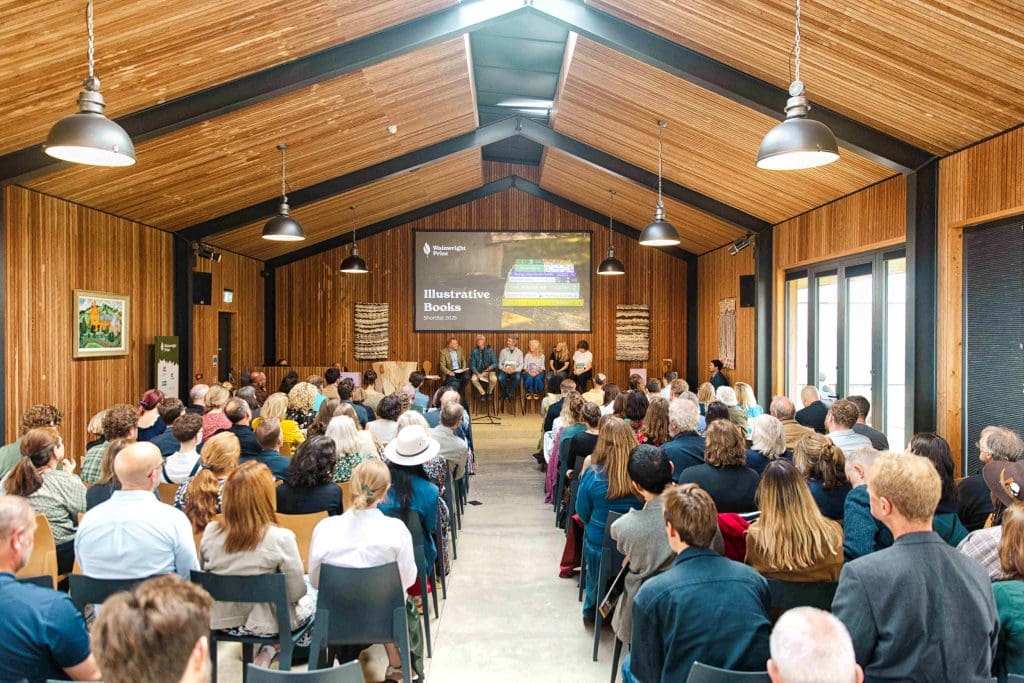 Wainwright-2025-2073 A room full of people listening to a panel of speakers at the 2025 Wainwright Prize event