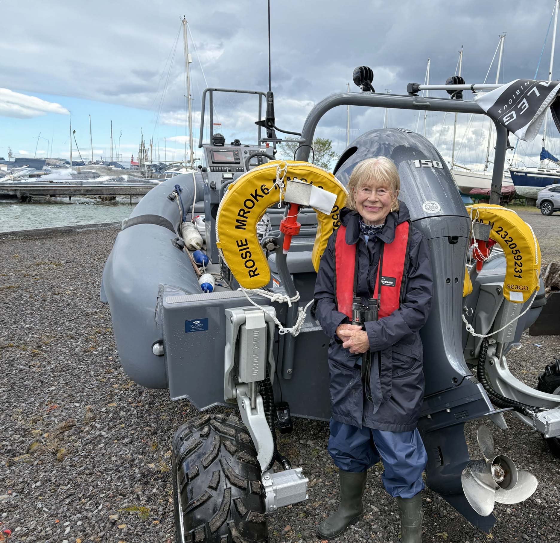 A woman poses in a lifejacket in front of a boat