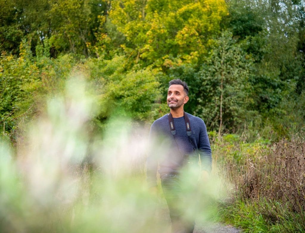 Dr Amir Khan walks through a nature reserve with binoculars around his neck