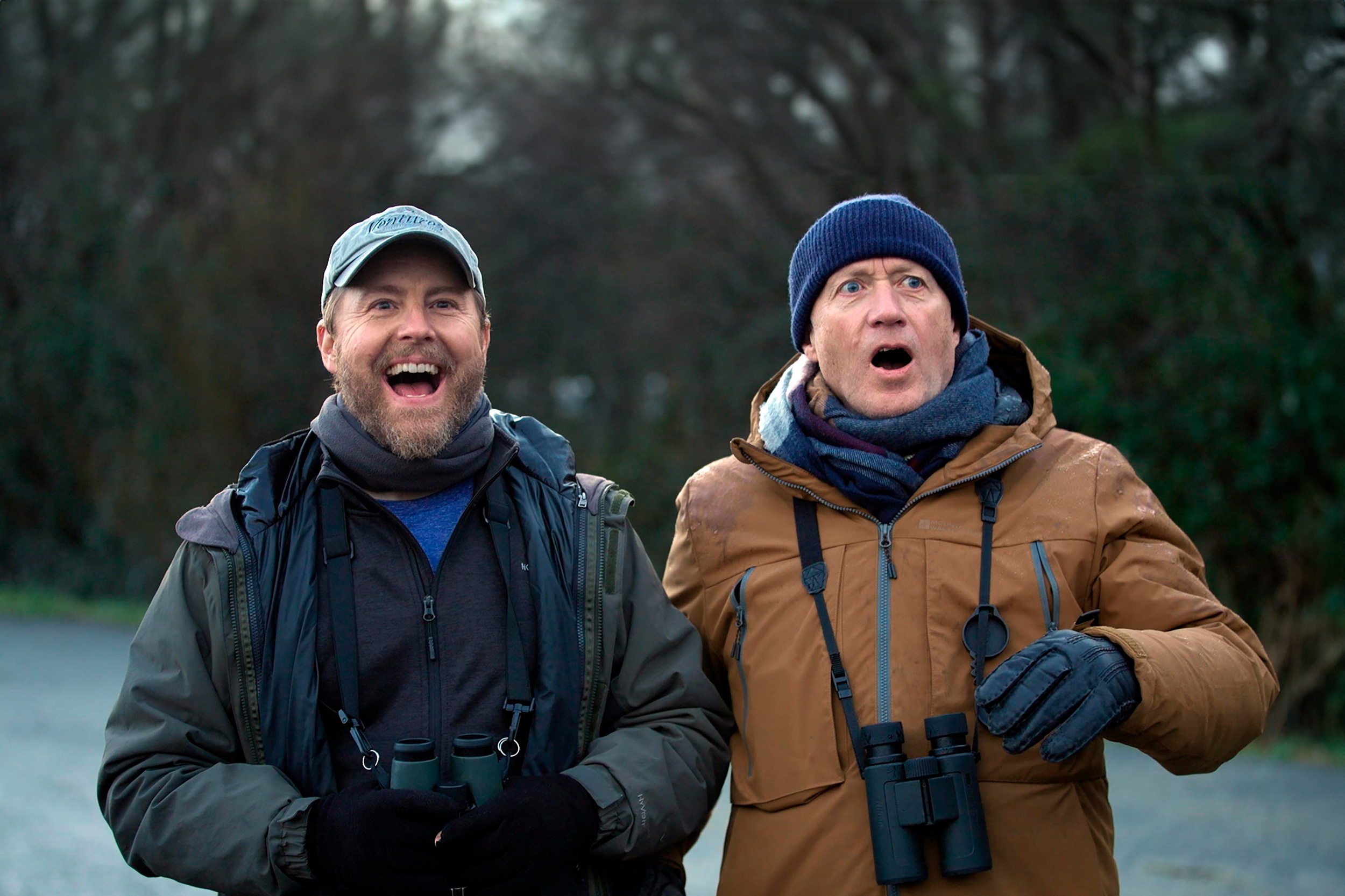 Sam has an open-mouth smile while Ade has a shocked expression as they see something out of shot