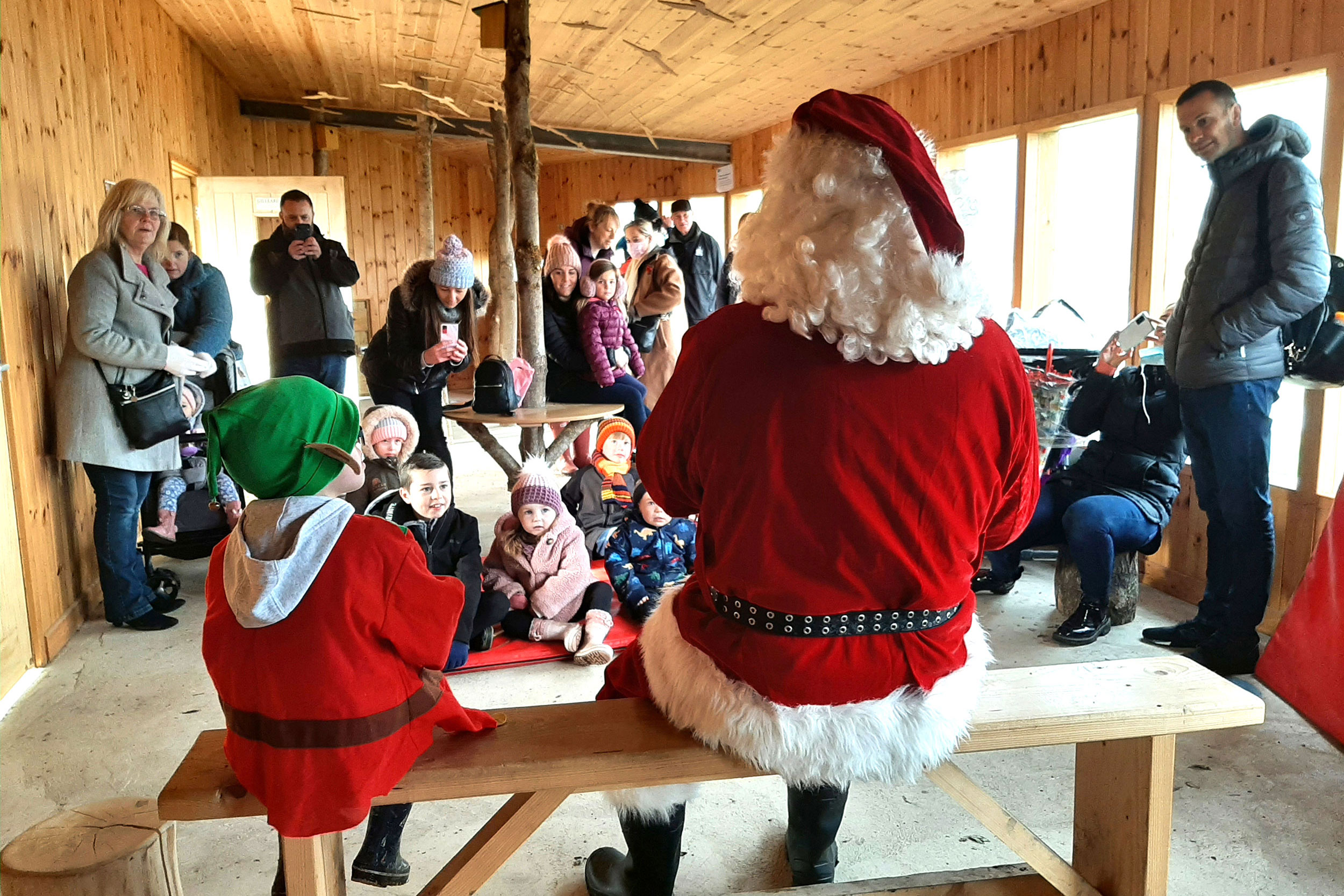 Families visit Father Christmas in a wooden hut at RSPB Old Moor