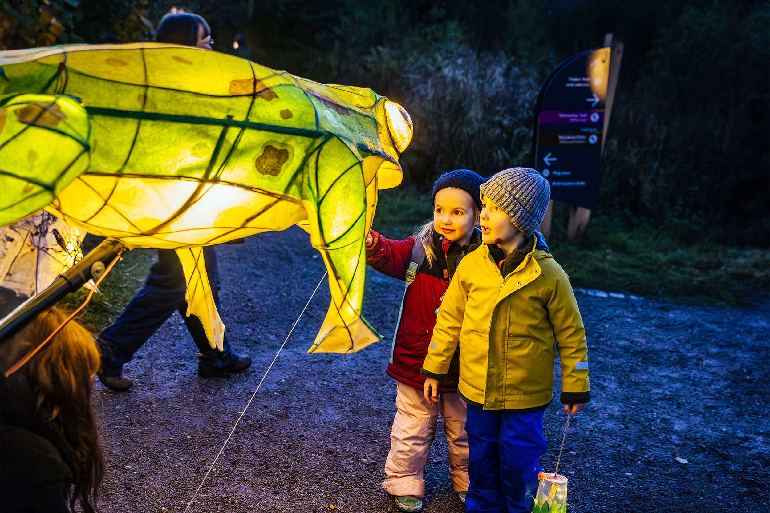 Two children looking at a large frog lantern on an RSPB trail