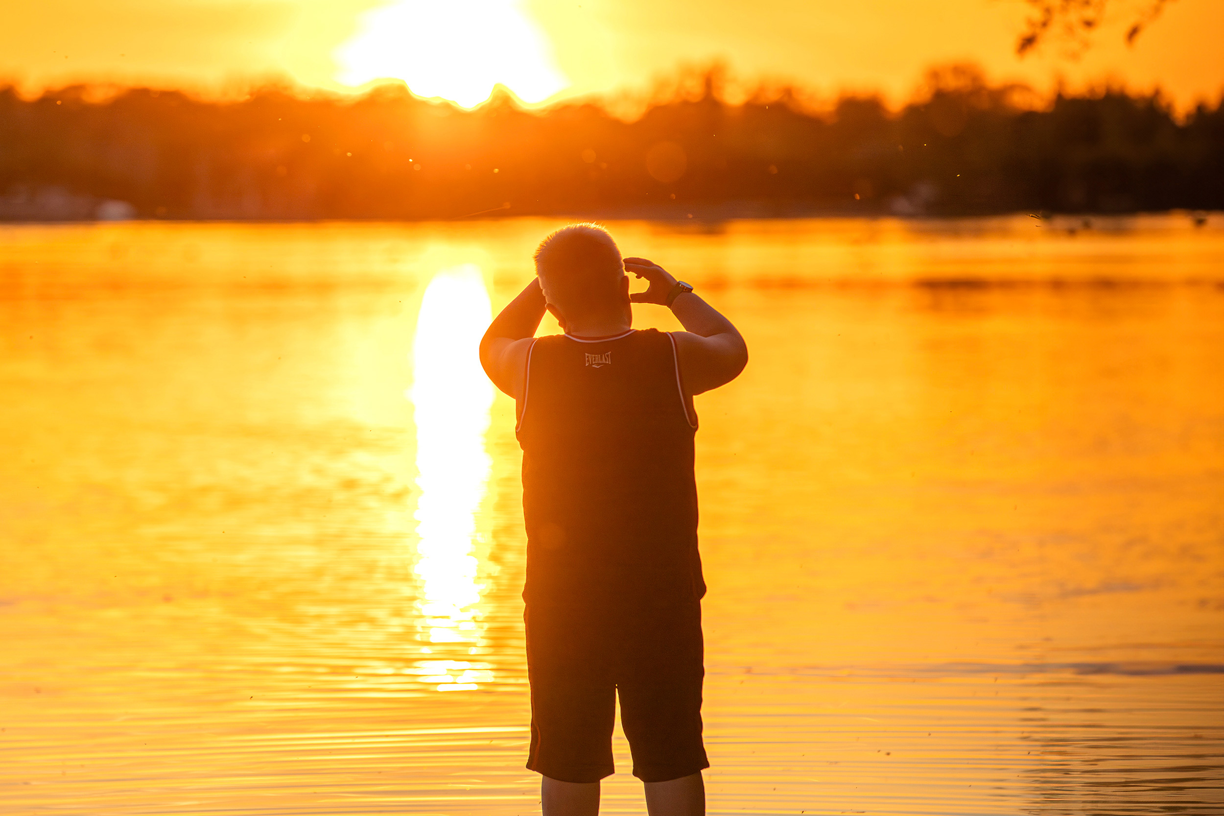 A young boy watches the sun set over a body of water