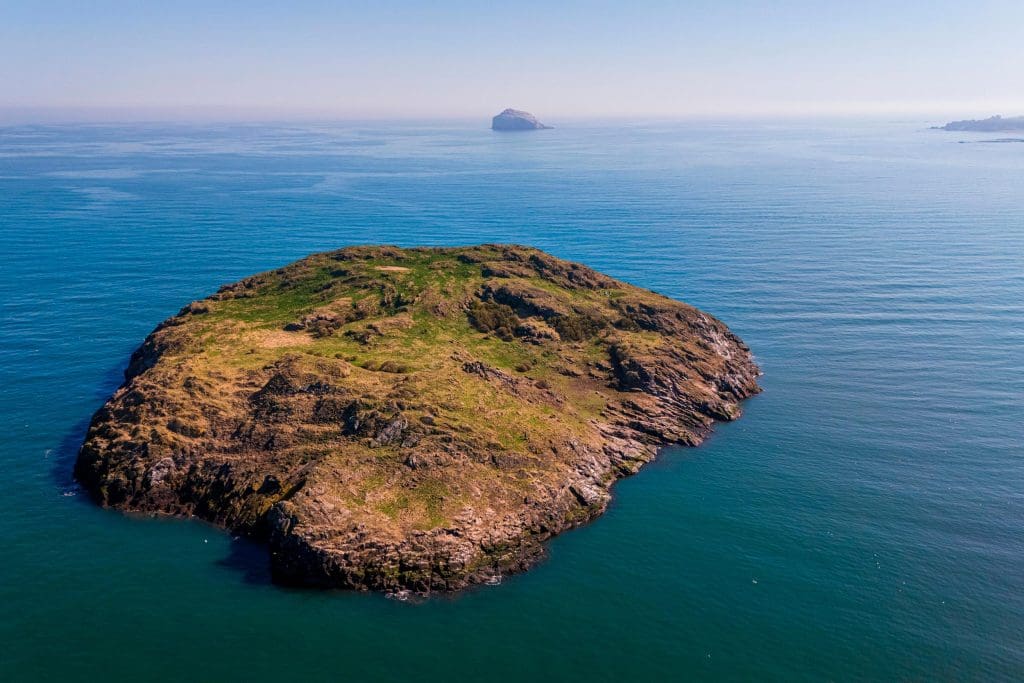 Craigleith-Island-with-Bass-Rock-in-Distance-©-Andy-Smith,-Scottish-Seabird-Centre An aerial shot showing two islands in the middle of the sea